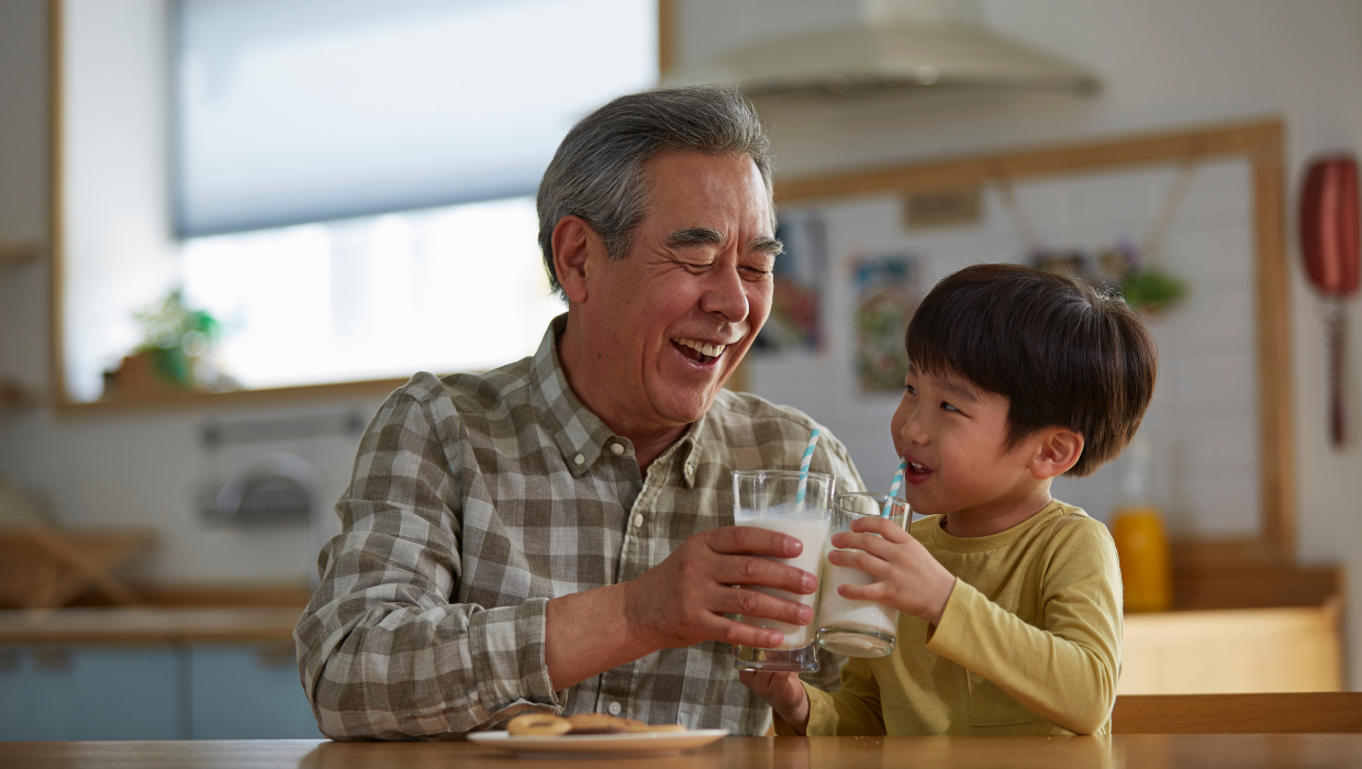 Grandfather having milk and cookies with grandson