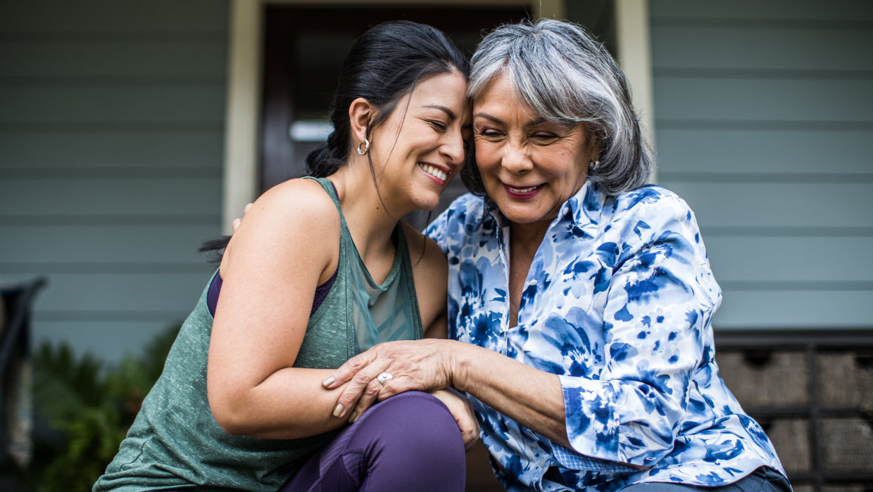 Adult daughter hugging mother on a front porch